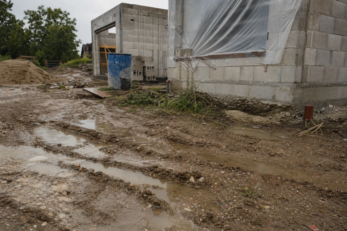 Chantier avec bâches, fûts et flaques d’eau stagnante